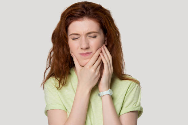 Head shot studio portrait redhead woman having tooth ache