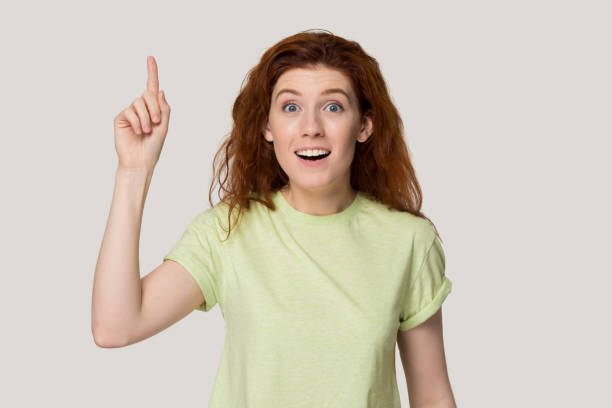 istock Red-headed woman point finger up find answer to question 1167561684
