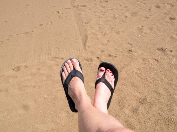 нога мужчины и женщины в шлепанцах в песке - flip flop human foot sand women стоковые фото и изобр�ажения