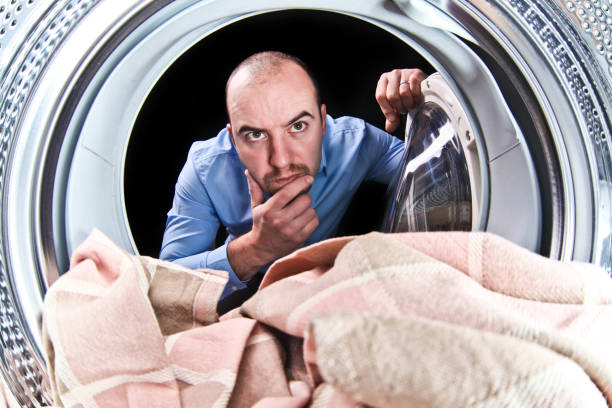 istock Thoughtful Man Looking At Textile In Washing Machine 1167562633