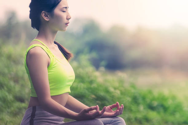 istock Side View Of Woman Meditating While Sitting On Grass 1167569178