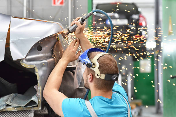 reparar la carrocería del coche por un mecánico en el taller - carrocería fotografías e imágenes de stock