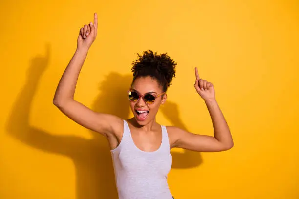 Photo of Close up photo beautiful nice pretty she her dark skin lady summer weekend rest relax dancing festive vacation fest modern moves motion wear sun specs casual tank-top isolated vivid yellow background