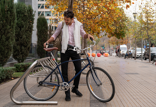 Happy businessman finishing a working day unlocking his bicycle - City Lifestyles