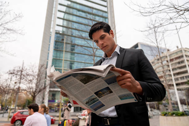 istock Handsome young businessman reading a newspaper outside 1167579837