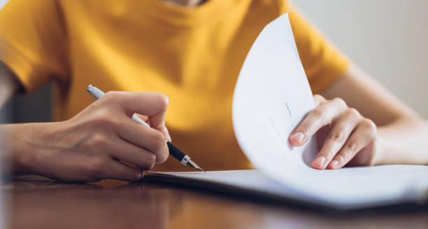 mujer firmando documento y mano sosteniendo la pluma poniendo la firma en papel, orden para autorizar sus derechos. - firma fotografías e imágenes de stock