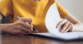 Woman signing document and hand holding pen putting signature at paper, order to authorize their rights.