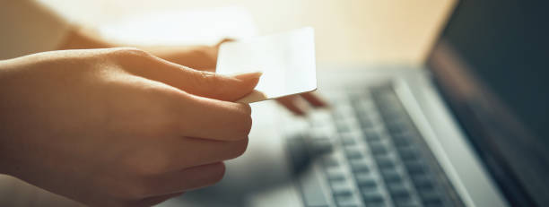 Hand holding credit card and press laptop computer enter the payment code for the product. Pay online for convenience.