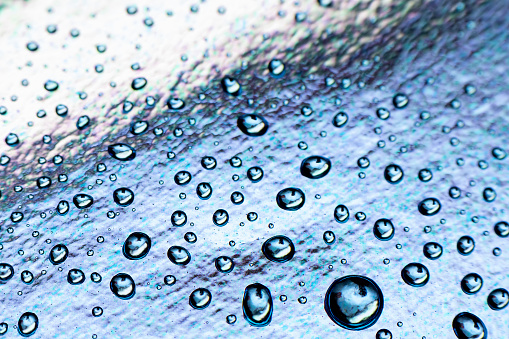 Water drops on blue foil background, close up