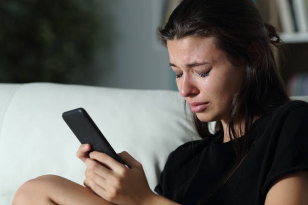 trieste tiener huilen na lees telefoon bericht - huilen stockfoto's en -beelden