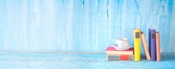 stack of multicolored hardback books with a cup of coffee, reading education, literature, panoramic, good copy space