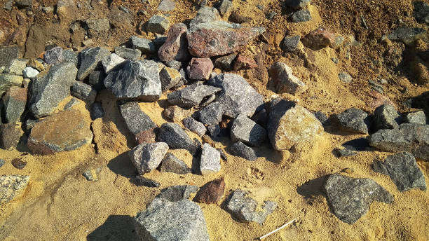 grandes pierres sur une plage sablonneuse. boulders de gris et brun sur le sable. la photo. - sandy brown bay beach sand photos et images de collection