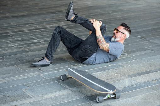 Mature hipster man falling and having an injury. About 45 years old, Caucasan male.