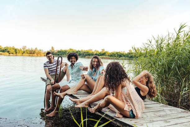 Group of friends sitting on a pier and having fun