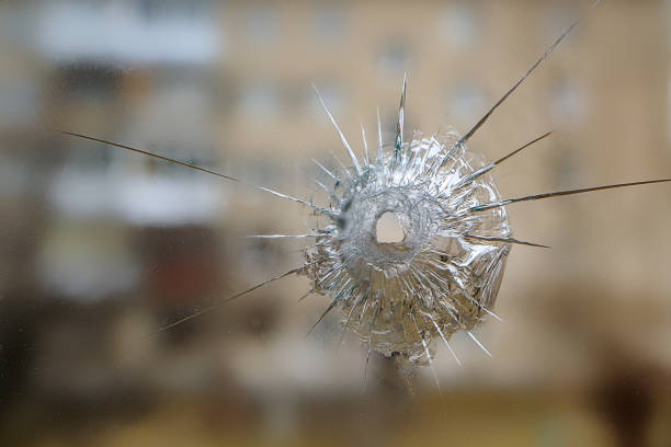 glass bullet cracks and splinters the background is blurred high-rise building