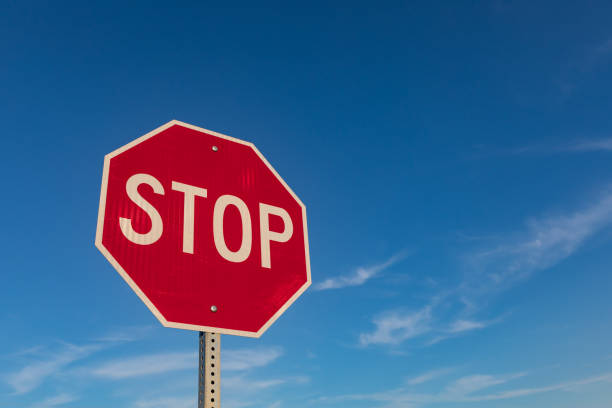 istock Isolated closeup looking up at red reflective stop sign with blue sky and white clouds in background 1167599716