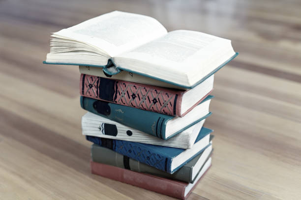 istock Stack of old books on wooden background. Opened book above. 1167603932