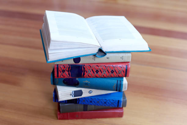 istock Stack of old books on wooden background. Opened book above. 1167604243