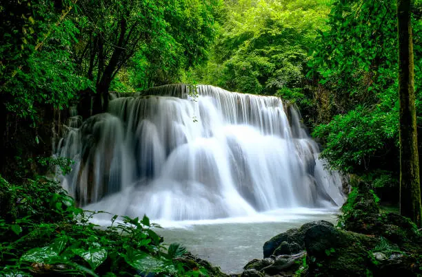 Photo of Multi-layered water fall with clouded and foggy like pattern in green forest with soft light