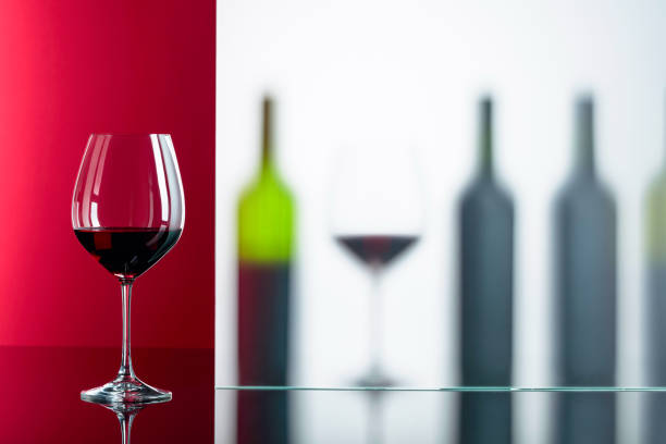 istock Bottles and glasses of red wine on a black reflective background. 1167607112