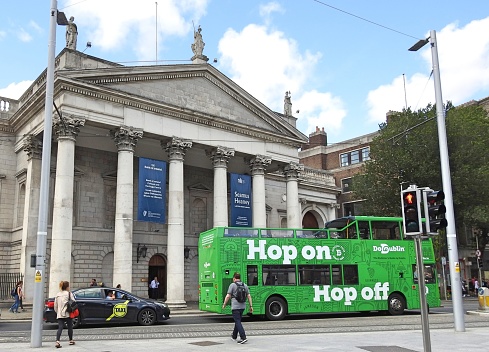 26th July 2019, Dublin, Ireland, A 'Hop on Hop off' sightseeing open top double decker tourist bus, with the Bank of Ireland, College Green, building in the background.