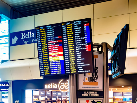 Luton, UK. Departure lounge at Luton Airport with franchises in the background selling food and flight information on the departure screens in the foreground.