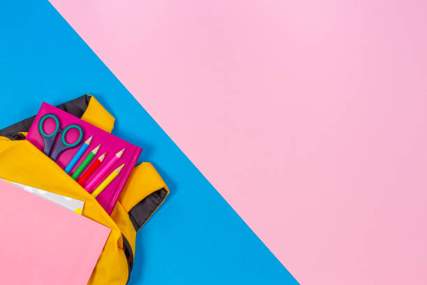 Back to school concept. Yellow backpack with school supplies on pastel pink and light blue background. Top view Back to school concept. Yellow backpack with school supplies on pastel pink and light blue background permanent marker photos stock pictures, royalty-free photos & images