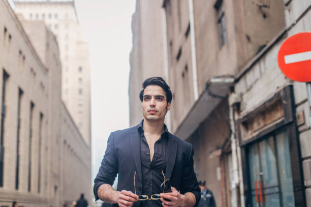 элегантный мужчина в черном костюме гуляет по улице - low angle view macho men urban scene стоковые фото и изображения