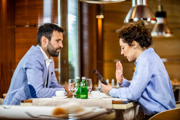 istock Businesswoman using a mobile phone while having a discussion with her colleague in a fancy restaurant 1167614606