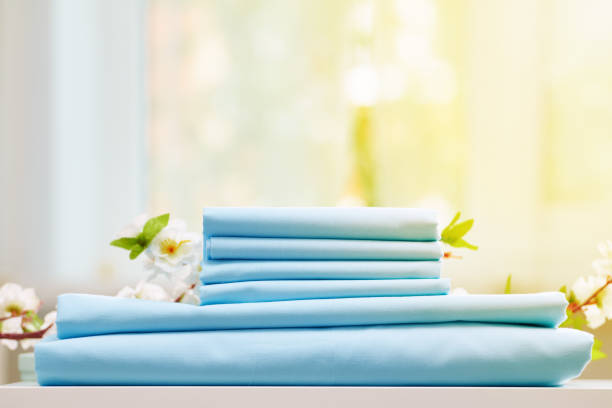istock A stack of blue folded bedding on a desk. Flowering branch. Blurred background. 1167618477