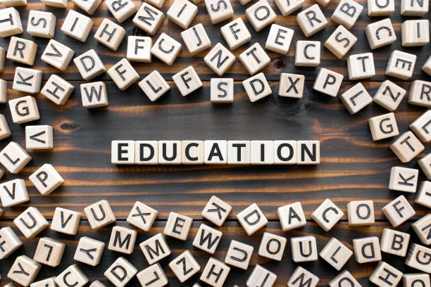 Education - word from wooden blocks with letters, school or college teaching or learning knowledge education  concept, random letters around, top view on wooden background
