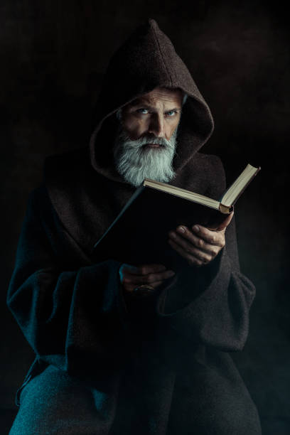 Senior monk wearing traditional clothes holding old book