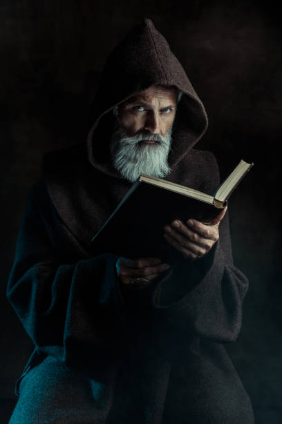 Senior monk wearing traditional clothes holding old book Fantasy portrait of senior monk holding old book merlin the wizard stock pictures, royalty-free photos & images
