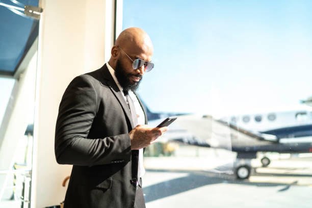 istock Businessman standing by the window and using smartphone in airport 1167623450