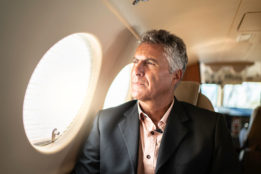 Mature man businessman looking through corporate jet window