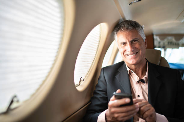 portrait of a businessman using smartphone in a private jet - corporate jet imagens e fotografias de stock