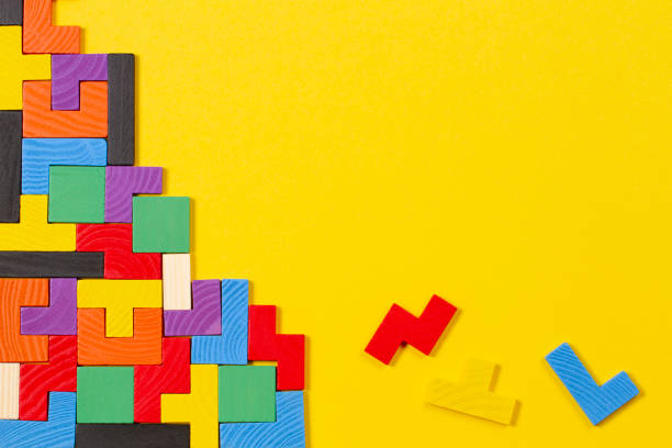 blocos de madeira das formas coloridas diferentes no fundo amarelo. vista superior - jogo de vídeo de empilhar blocos - fotografias e filmes do acervo