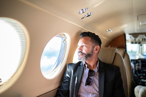 Mature man businessman looking through corporate jet window