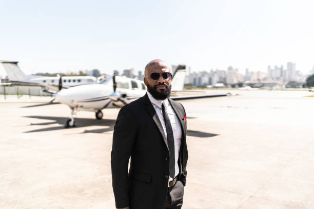 Portrait of businessman standing in front of corporate jet Portrait of businessman standing in front of corporate jet rich black men pictures stock pictures, royalty-free photos & images