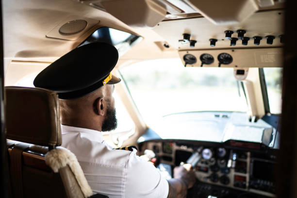 Airline Pilot gazing intently at the instruments with the early morning sun bursting through the window
