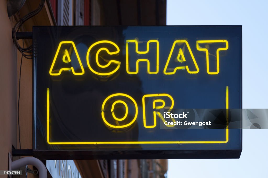 Neon light - Achat or Close-up on a neon light shaped into the short phrase "Achat or" (French for: Gold purchase) above a gold retailer. Business Stock Photo