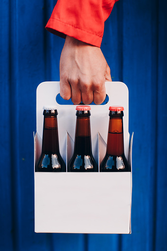 Man's Hand holding a six pack of brown beer bottles