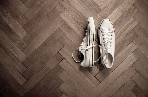 Pair of canvas shoes on parquet floor, toned image