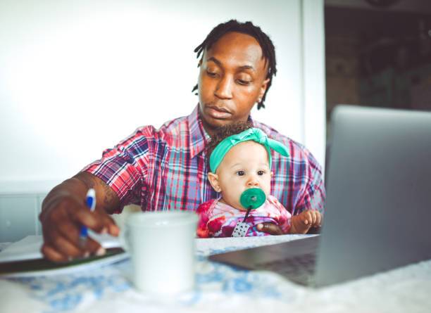 istock African American dad works on a computer with his infant daughter work from home modern masculinity 1167634098
