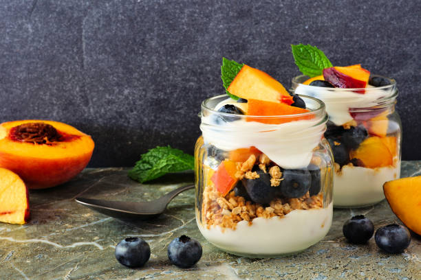 istock Peach and blueberry parfaits in mason jars against dark stone 1167634325
