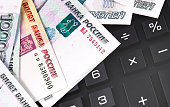 finance concept in closeup black calculator with Russian money, rubles banknotes background