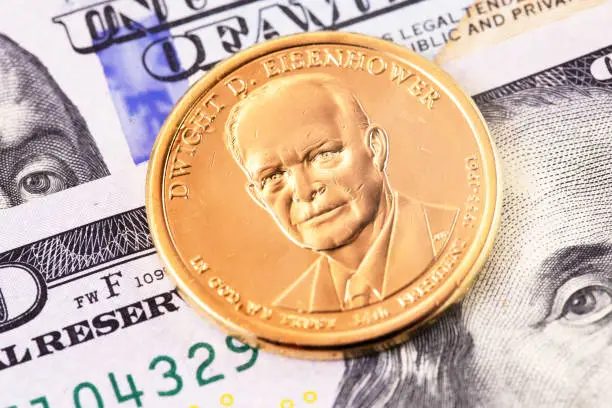 macro one dollar golden coin with Dwight D. Eisenhower portrait, and hundred dollars banknotes