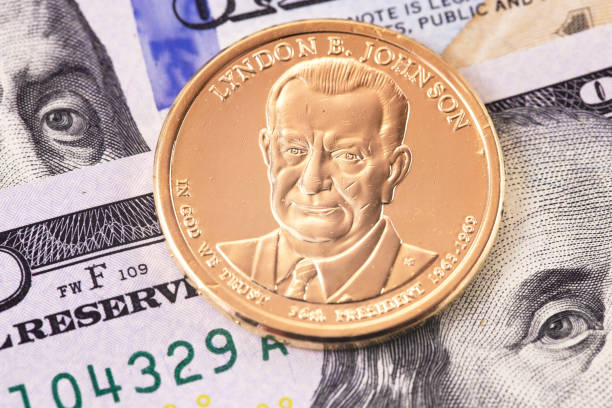 one dollar golden coin with Lyndon Baines Johnson portrait, and hundred dollars banknotes stock photo