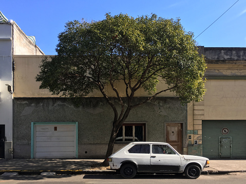 Buenos Aires, Argentina - August 11, 2019: Little white old car parked in the street next to house. A lot of cars like this can still be seen in the city