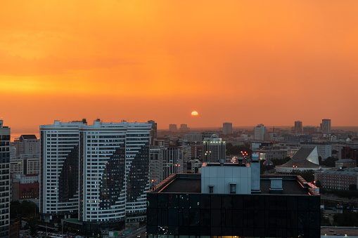 Orange sunset and smog over the evening city.